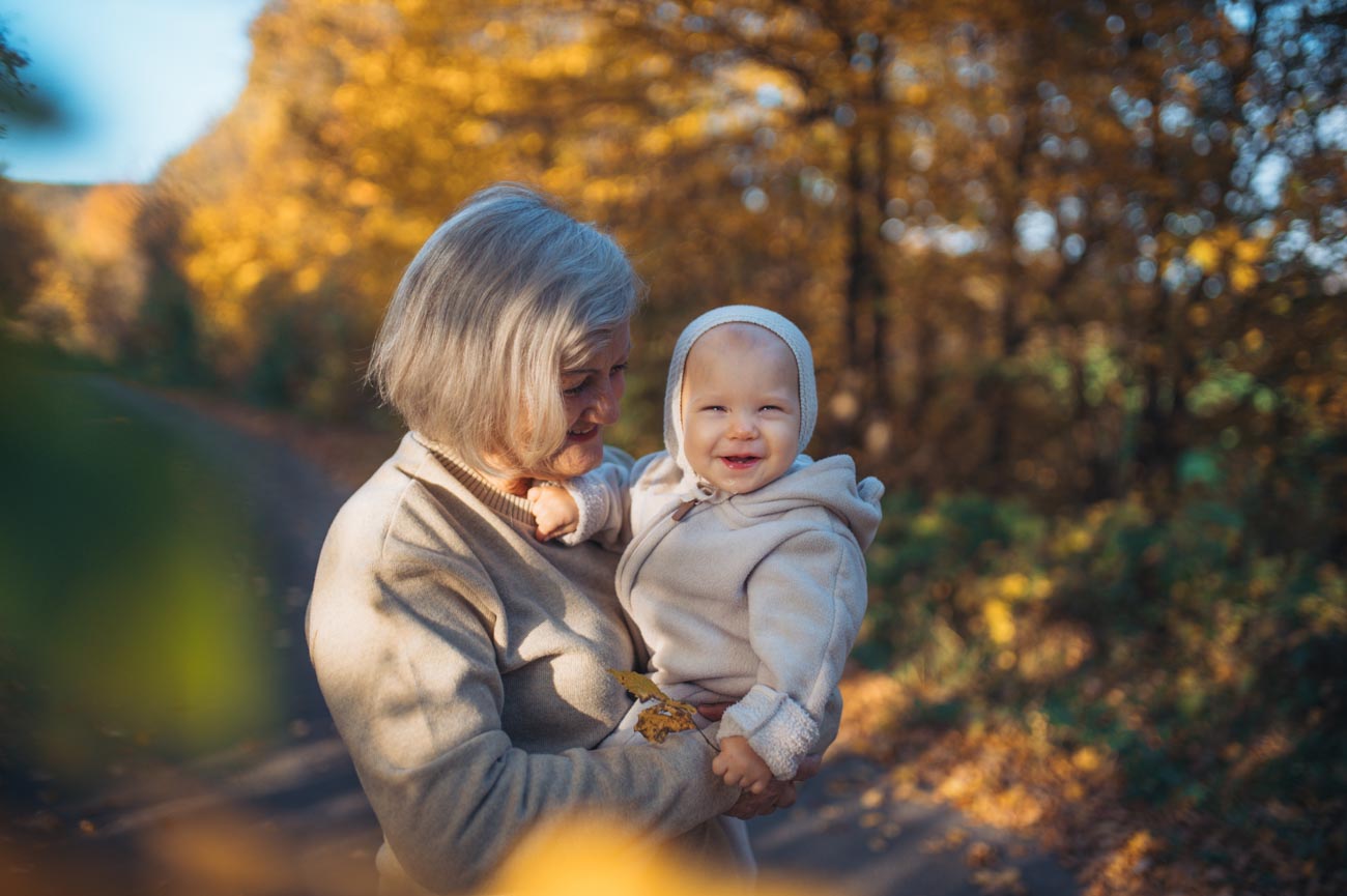 Grandma,Holding,Baby,In,Warm,Embrace,During,Fall,Season.